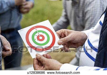 Stock Photograph - Men looking at bulls eye at rifle target shooting, Florence, Italy. Fotosearch