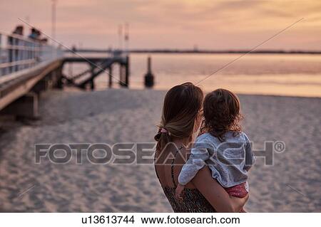 Picture - Mother and baby girl enjoying beach at sunset, Arcachon, France. Fotosearch