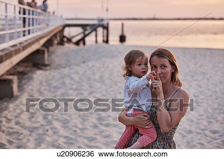 Stock Photograph - Mother and baby girl enjoying beach at sunset, Arcachon, France. Fotosearch
