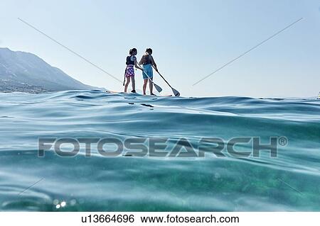 Stock Photograph - Mother and daughter paddling in sea, Paleros, Greece. Fotosearch