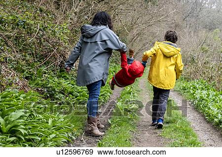 Mother and sons walking together on a rainy misty day in woodland. View Large Photo Image Stock Photo - Mother and sons walking together on a rainy misty day in woodland.. Fotosearch