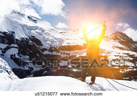 Stock Photo - Mountaineer celebrating from reaching the summit of mountain. Fotosearch