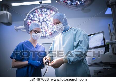 Nurse and surgeon in operating theatre in hospital setting View Large Photo Image Stock Photograph - Nurse and surgeon in operating theatre in hospital setting. Fotosearch