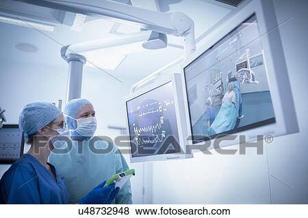 Nurse and surgeon inspecting screens in operating theatre in hospital setting View Large Photo Image Stock Photo - Nurse and surgeon inspecting screens in operating theatre in hospital setting. Fotosearch