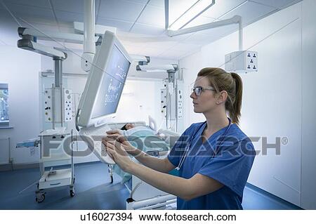 Picture - Nurse inspecting screen in intensive care unit in hospital setting. Fotosearch