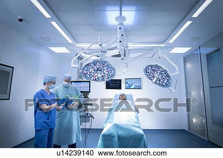 Stock Image - Nurses, surgeon and patient in operating theatre in hospital setting. Fotosearch