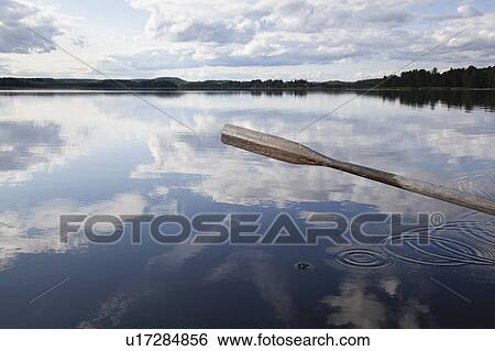 Stock Photograph - Oar, reflection of cloudscape in lake, Finland. Fotosearch