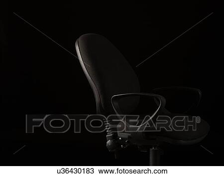 Stock Image - Office chair on black background. Fotosearch