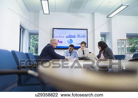 Stock Image - Office workers in meeting with graphs and charts. Fotosearch