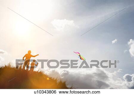 Stock Photograph - Parent with child playing with kite on the top of the hill. Fotosearch