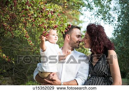Stock Photo - Parents with son kissing in park. Fotosearch