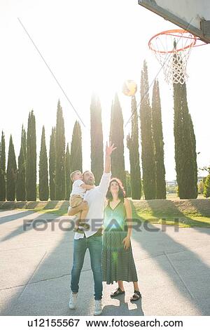 Stock Photo - Parents with son playing netball in park. Fotosearch