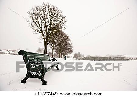 Stock Photo - Park bench and park covered in snow. Fotosearch