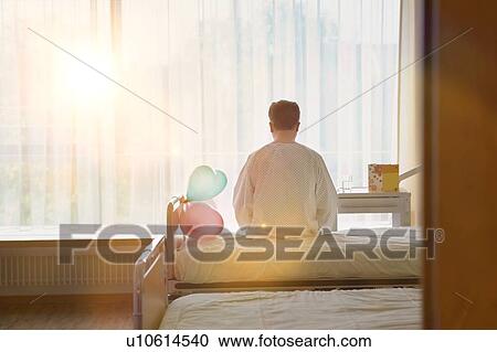 Stock Image - Patient Sitting on Hospital Bed with strong lens flare. Fotosearch