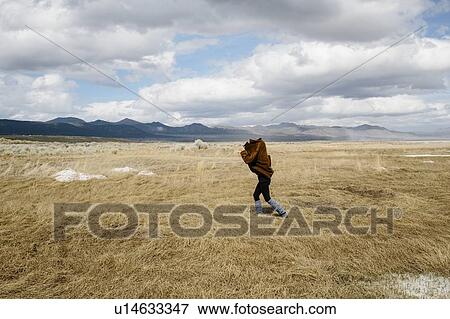 Stock Photo - Person walking with jacket over head in countryside, Mammoth, California, USA. Fotosearch