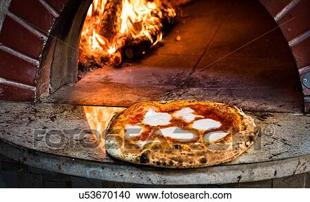 Stock Image - Pizza removed from stone oven. Fotosearch