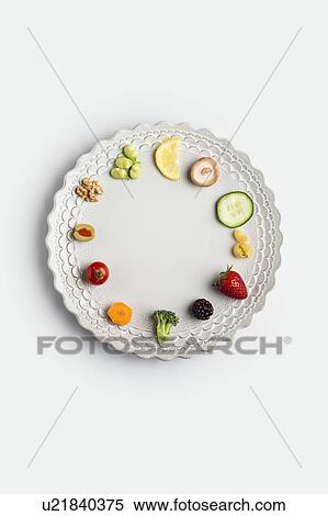 Stock Photography - Plate with fresh fruits and vegetables arranged as a clock. Fotosearch