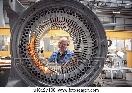 Stock Photo - Portrait of electrical engineer with generator stator in electrical engineering factory. Fotosearch