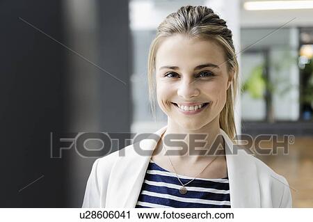 Stock Image - Portrait of female student at corridor of office building. Fotosearch