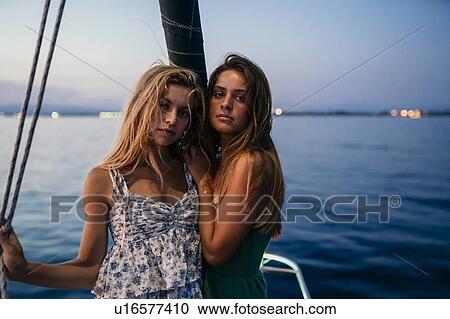 Stock Image - Portrait of friends on sailboat in evening, Italy. Fotosearch
