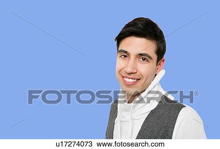 Stock Image - Portrait of handsome young indian man over blue background. Fotosearch