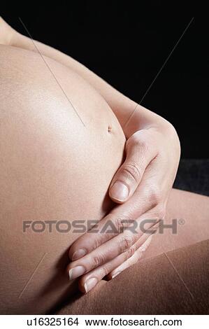 Picture - Pregnant woman holding baby bump. Fotosearch