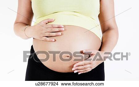 Picture - Pregnant woman holding her baby bump. Fotosearch