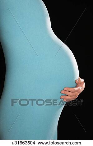 Picture - Pregnant woman in body suit holding abdomen. Fotosearch