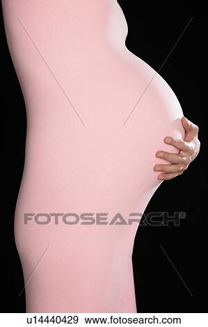 Stock Photo - Pregnant woman in body suit holding abdomen. Fotosearch