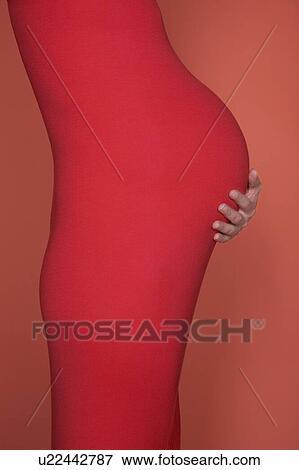 Stock Photo - Pregnant woman in body suit holding abdomen. Fotosearch