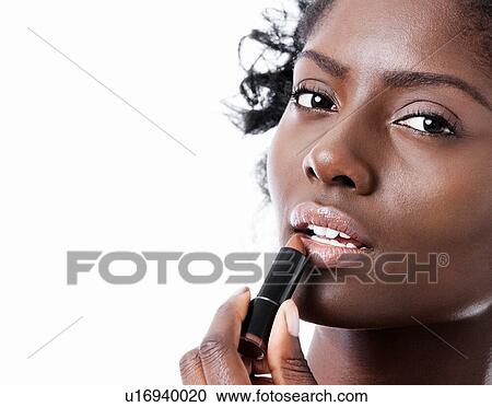 Stock Image - Pretty Black woman applying lipstick. Fotosearch