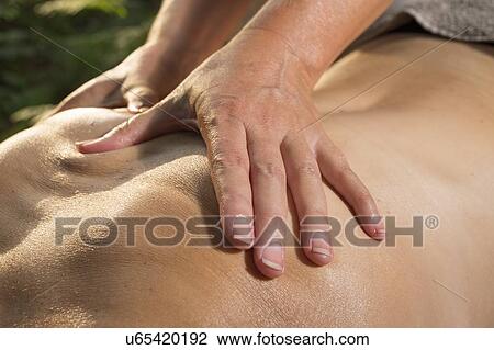 Stock Image - Professional masseuse treats woman on massage table in woods. Fotosearch