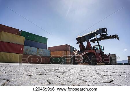 Stock Photograph - Reach stacker and shipping containers in dock. Fotosearch