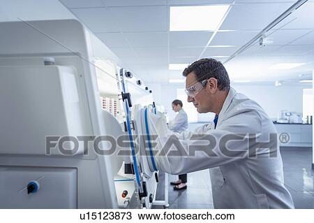 Stock Image - Scientist making bacterial culture on agar dish in anaerobic cabinet in laboratory. Fotosearch