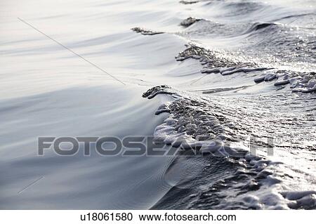 Stock Image - Sea foam and wave on sunny day. Fotosearch