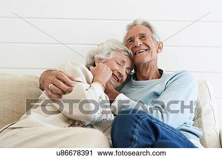 Stock Image - Senior Couple Hugging on Sofa. Fotosearch