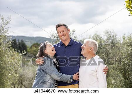 Stock Image - Senior couple with son, olive trees in background, Florence, Italy. Fotosearch