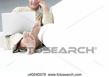 Senior man on laptop sitting on couch View Large Photo Image Stock Photo - Senior man on laptop sitting on couch. Fotosearch