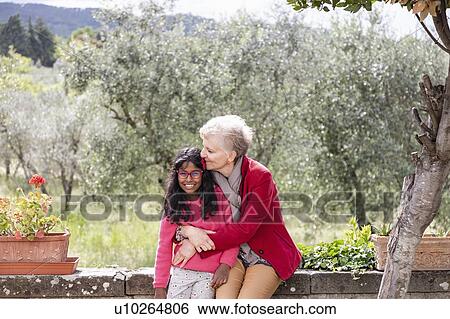 Stock Photograph - Senior woman with granddaughter, olive trees in background, Florence, Italy. Fotosearch