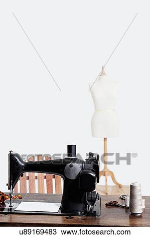 Stock Image - Sewing machine with threads over gray background. Fotosearch