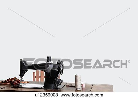 Stock Photo - Sewing machine with threads over gray background. Fotosearch