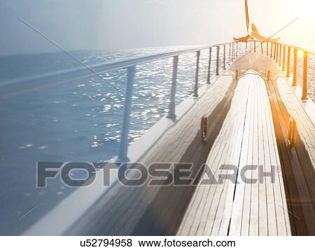 Stock Photo - Side of luxury yacht with couple legs sunbathing in sunshine. Fotosearch