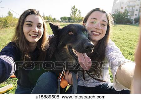 Sisters taking selfie with dog in park View Large Photo Image Stock Photo - Sisters taking selfie with dog in park. Fotosearch