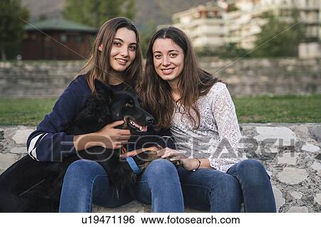 Stock Photograph - Sisters with dog in park. Fotosearch