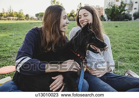Sisters with dog talking in park View Large Photo Image Stock Image - Sisters with dog talking in park. Fotosearch