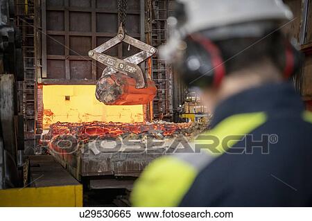 Steelworker watching red hot steel ingot being craned out of furnace in steelworks View Large Photo Image Stock Photography - Steelworker watching red hot steel ingot being craned out of furnace in steelworks. Fotosearch