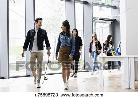 Stock Image - Students talking and walking in college premise. Fotosearch