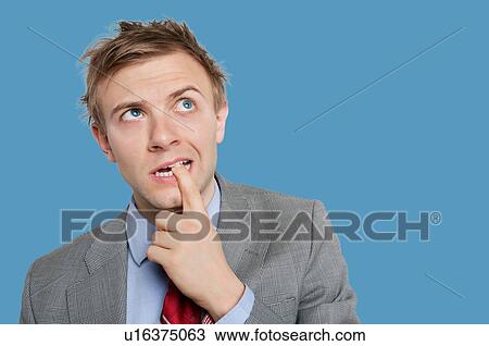 Thoughtful young businessman biting finger while looking up View Large Photo Image Stock Image - Thoughtful young businessman biting finger while looking up. Fotosearch