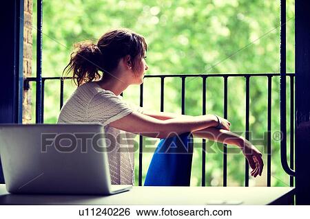 Thoughtful young businesswoman sitting at desk by balcony View Large Photo Image Stock Photograph - Thoughtful young businesswoman sitting at desk by balcony. Fotosearch
