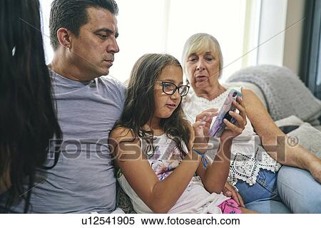 Stock Photography - Three generation family enjoying computer games on sofa. Fotosearch